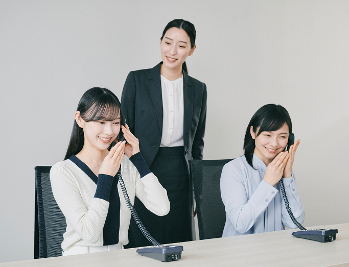 新人スタッフが電話研修を受けている写真
