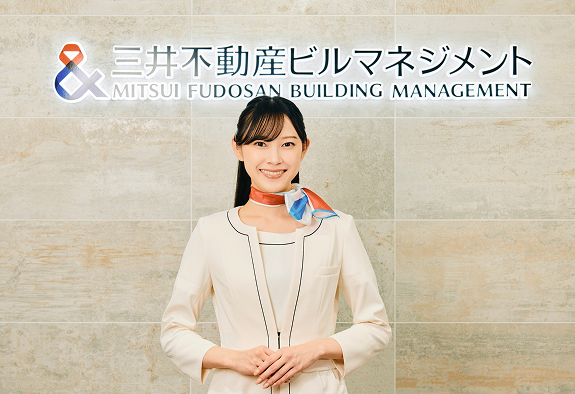 受付スタッフが社名ロゴの前で立っている写真