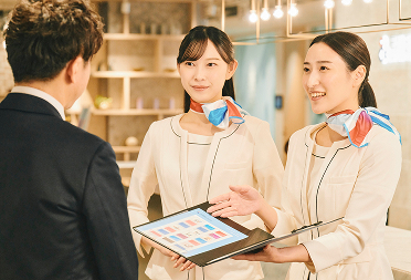 受付スタッフが来訪者にタブレットで案内している写真